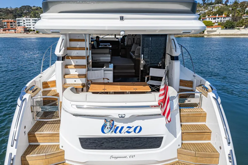 Slide: The Image of 2022 Princess F55 yacht with wooden deck, docked near a beach, displaying an American flag. - 26