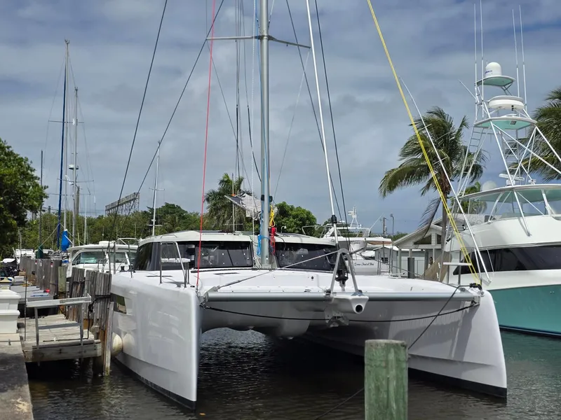 The Image of 2025 Seawind 1370 catamaran docked at a marina, surrounded by palm trees and boats. - 1