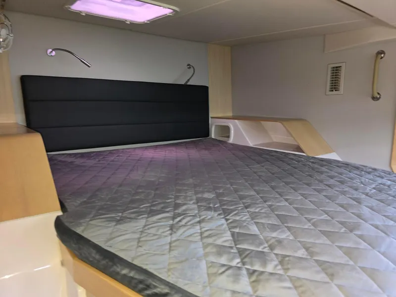 Slide: The Image of 2025 Seawind 1370 cabin interior with quilted bed, modern design, and soft lighting. - 24