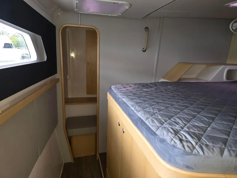 Slide: The Image of Seawind 1370 (2025) cabin interior with bed, window, and wooden accents. - 26