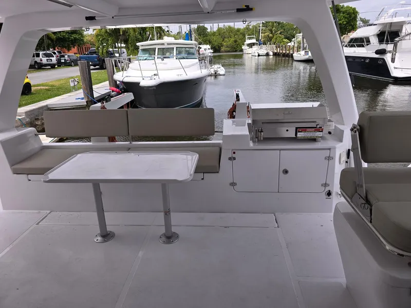 Slide: The Image of 2025 Seawind 1370 yacht interior with seating, table, and docked boats in the background. - 5