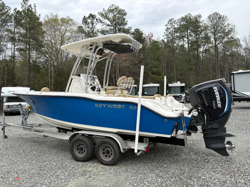 Slide: The Image of 2017 Key West 219fs boat on trailer with Evinrude motor, parked outdoors. - 2