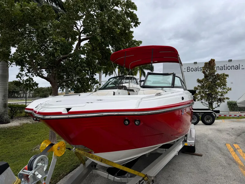 Slide: The Image of Red 2020 Monterey M-45 boat on trailer, parked outdoors near trees and building. - 2