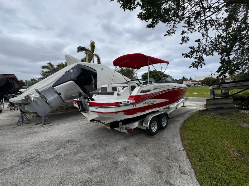 Slide: The Image of 2020 Monterey M-45 boat with red canopy on trailer, parked outdoors. - 3