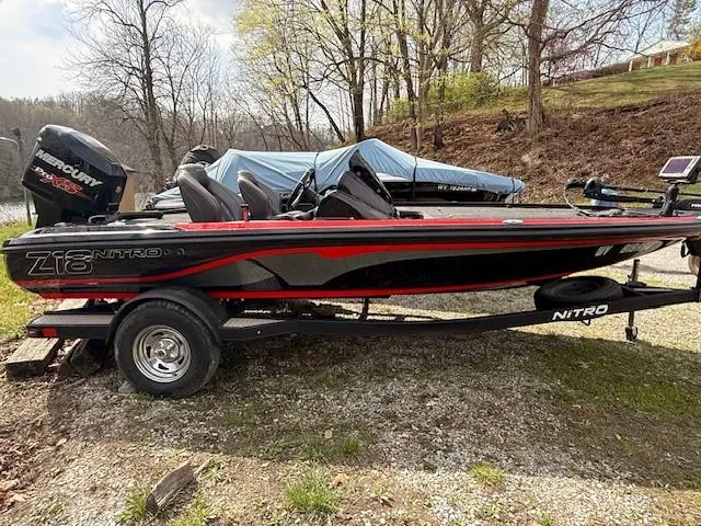 Slide: The Image of 2018 Nitro Z18 boat with trailer, parked outdoors near trees. - 0