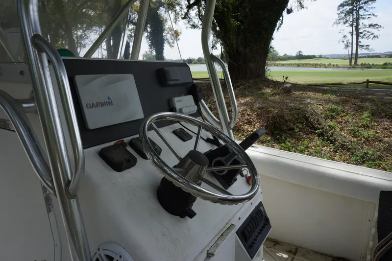 Slide: The Image of Edgewater 225CC 2002 boat console with Garmin navigation, steering wheel, and outdoor view. - 12