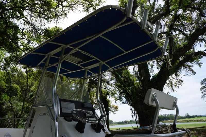 Slide: The Image of Edgewater 225CC 2002 boat with canopy, steering console, and rod holders, set against a tree-lined background. - 6