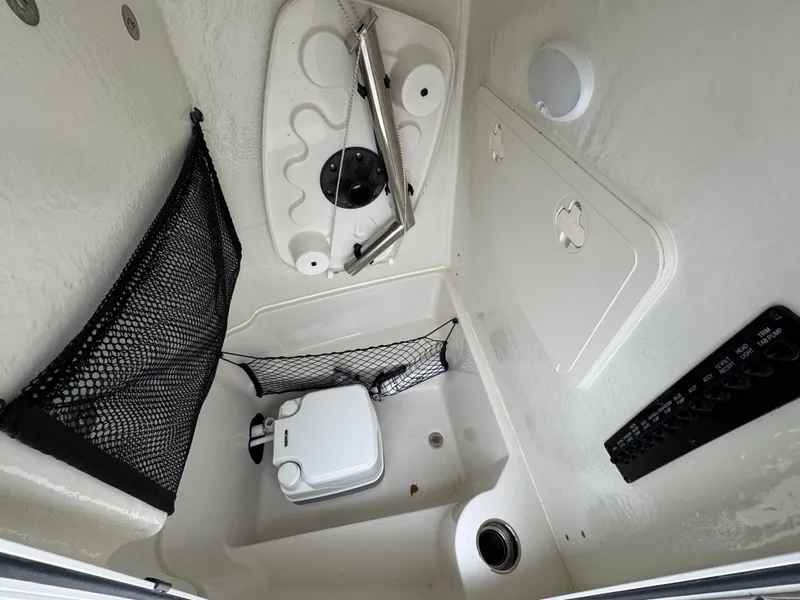 Slide: The Image of 2024 Sailfish 220 CC boat interior with storage nets and portable toilet. - 16