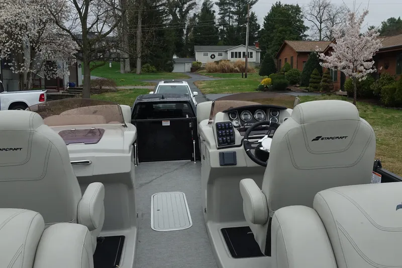 Slide: The Image of 2021 Starcraft SLS 5 DC boat interior with steering wheel and seating, parked in residential area. - 16