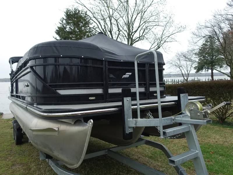 Slide: The Image of 2021 Starcraft SLS 5 DC pontoon boat on trailer, covered, parked near lake. - 2