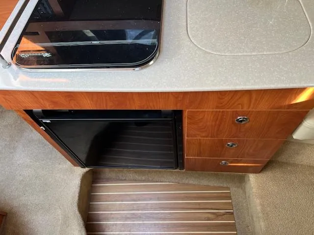 Slide: The Image of Interior view of 2009 Bayliner 245 Cruiser kitchen area with stove and fridge. - 12