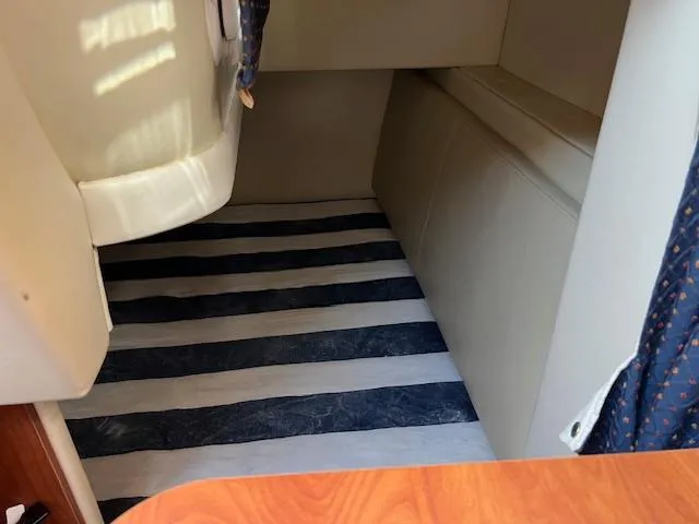 Slide: The Image of 2009 Bayliner 245 Cruiser interior with striped bedding and cozy cabin space. - 13