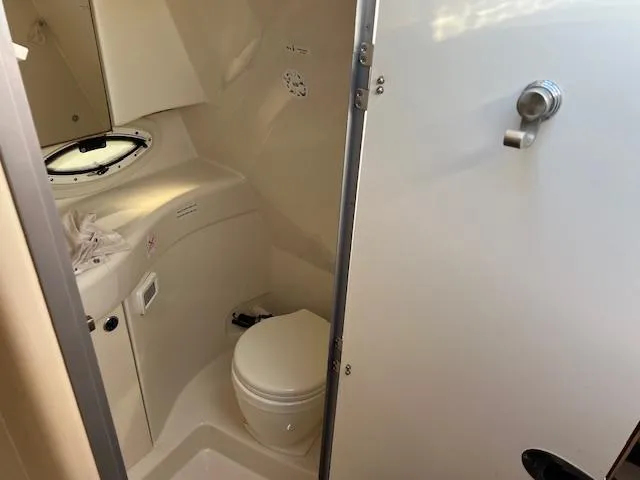 Slide: The Image of 2009 Bayliner 245 Cruiser bathroom interior with toilet and porthole window. - 15
