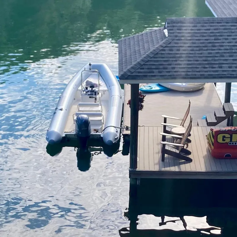 Slide: The Image of 2011 Novurania NE70 boat docked beside a lakeside deck with chairs and inflatables. - 4