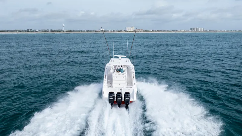Slide: The Image of 2024 SeaHunter 35 Tournament boat cruising on open water, rear view. - 8