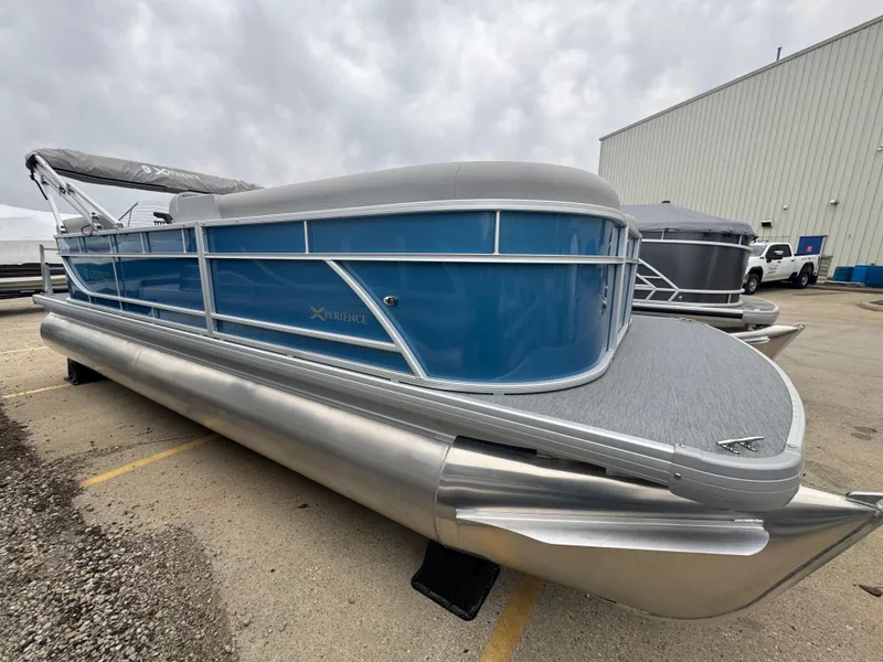 Slide: The Image of 2025 Godfrey EX2286SBX pontoon boat with blue exterior, parked outdoors. - 1