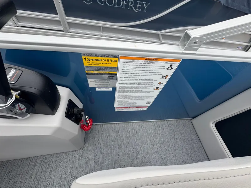 Slide: The Image of 2025 Godfrey EX2286SBX boat interior with capacity warning label and control panel. - 17