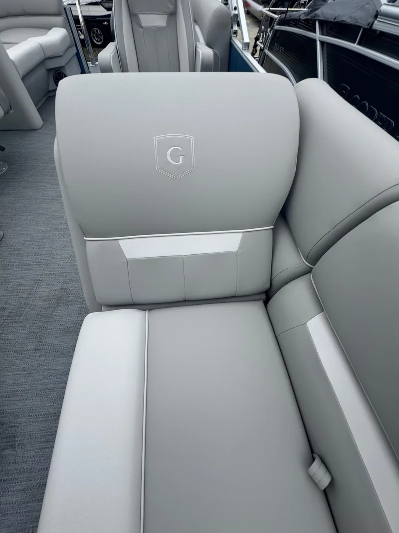 Slide: The Image of 2025 Godfrey EX2286SBX boat interior with gray seating and embroidered logo. - 5
