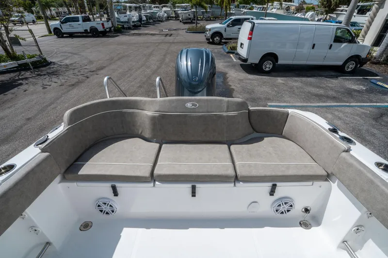 Slide: The Image of 2025 Sea Hunt Ultra 234 boat with cushioned seating and outboard motor in a parking lot. - 10