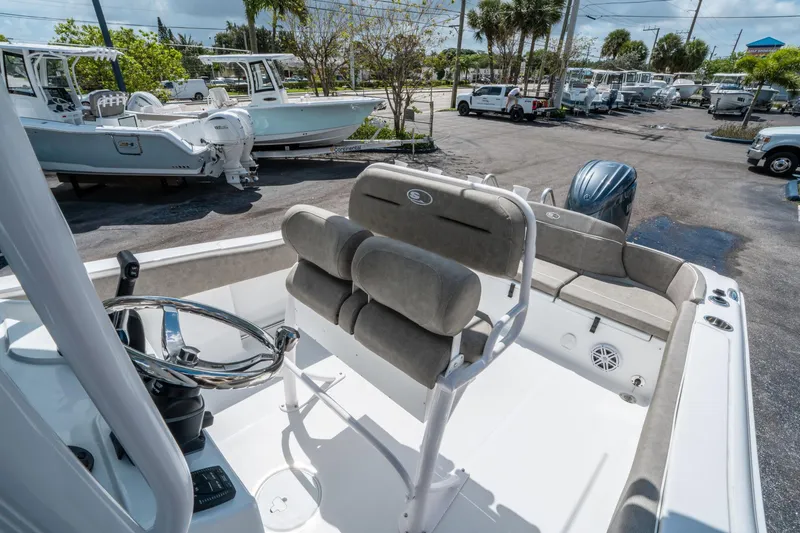 Slide: The Image of 2025 Sea Hunt Ultra 234 boat interior with steering wheel and seating, parked in a marina. - 18