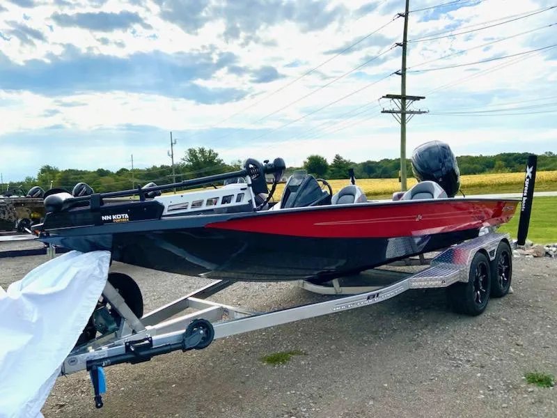 The Image of 2024 Xpress X19 Pro boat on trailer, red and black design, parked outdoors. - 1