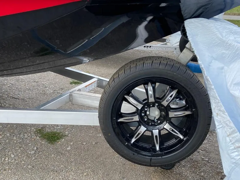 Slide: The Image of 2024 Xpress X19 Pro boat trailer with black alloy wheel on gravel. - 13