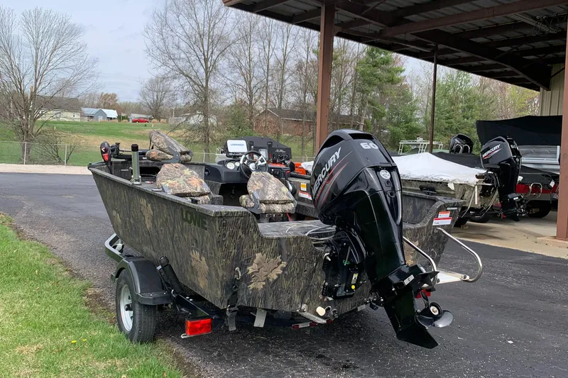 Slide: The Image of 2014 Lowe FM 165 Pro SC fishing boat with Mercury outboard motor, parked outdoors. - 3