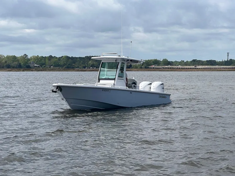 Slide: The Image of 2022 Everglades 273 Center Console boat on a calm lake under cloudy skies. - 2