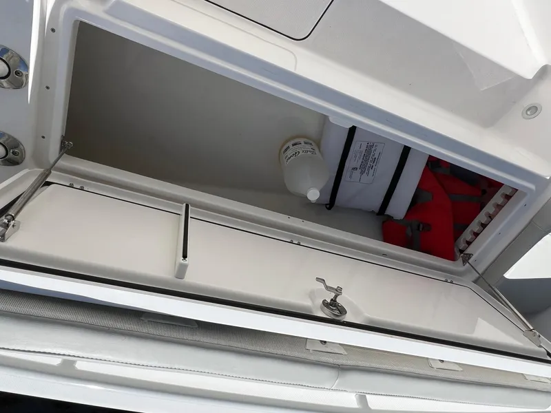 Slide: The Image of Storage compartment on 2022 Everglades 273 CC boat, featuring safety equipment and supplies. - 23