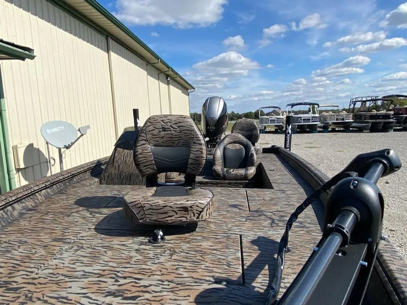 Slide: The Image of 2024 Xpress XP185 Catfish boat with camo seats, parked outdoors under a blue sky. - 13