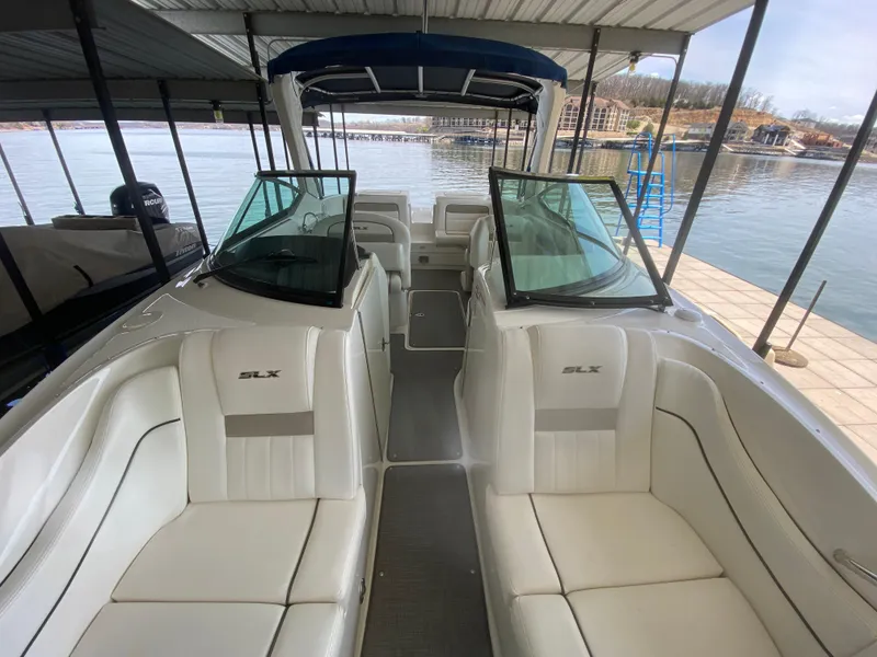 Slide: The Image of 2010 Sea Ray 300 SLX boat interior with white seating, docked by a calm lake. - 43