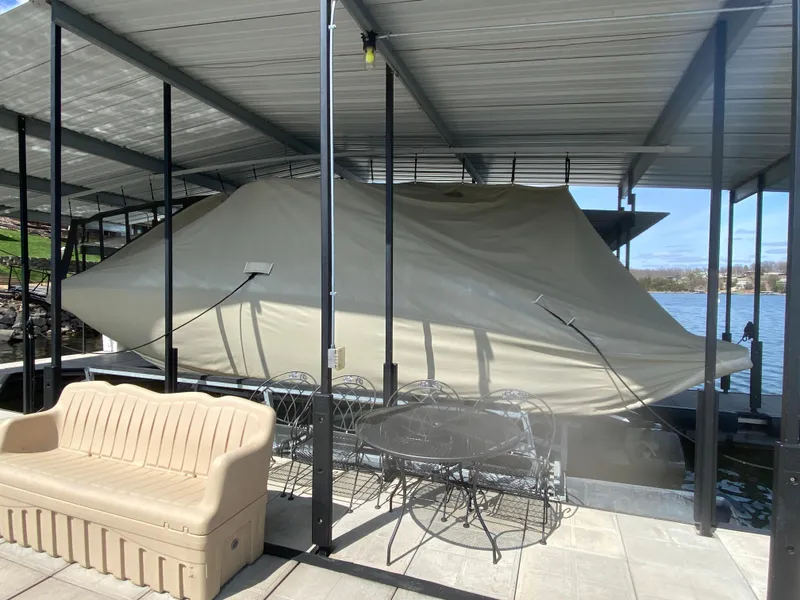 Slide: The Image of Covered 2010 Sea Ray 300 SLX boat docked under a metal canopy with patio furniture nearby. - 48
