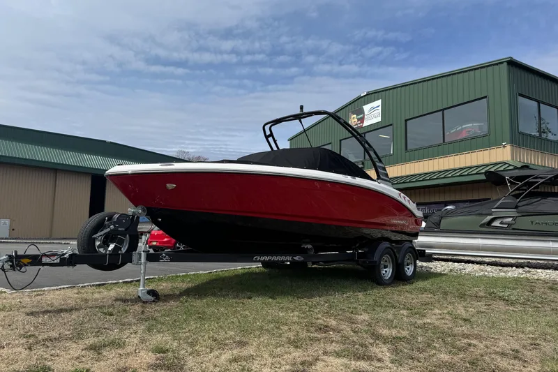 Slide: The Image of 2025 Chaparral 21 SSi boat on trailer, red hull, parked outdoors near green building. - 2
