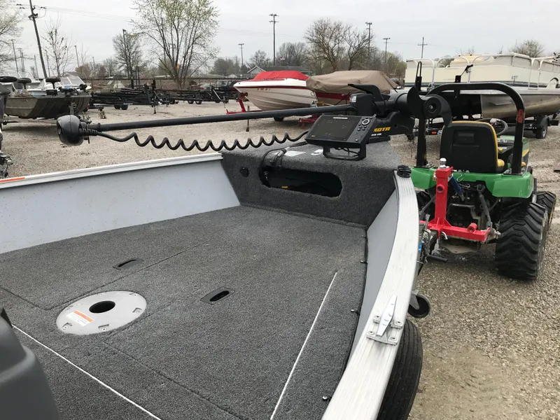 Slide: The Image of 2016 Lund 1600 Rebel SS boat with trolling motor and tractor in a yard. - 16