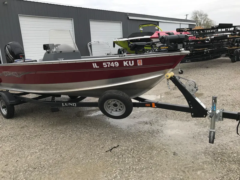 Slide: The Image of 2016 Lund 1600 Rebel SS boat on trailer, parked outside a garage. - 6