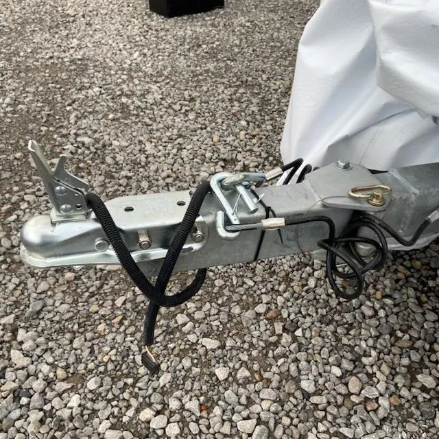 Slide: The Image of 2024 Xpress H18C trailer hitch on gravel surface, secured with safety cables. - 9