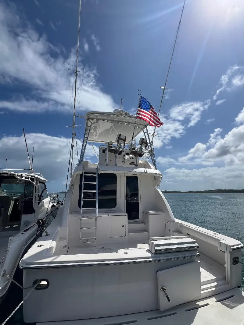 Slide: The Image of 2009 Bertram 45 Convertible yacht with American flag, docked under a sunny sky. - 3