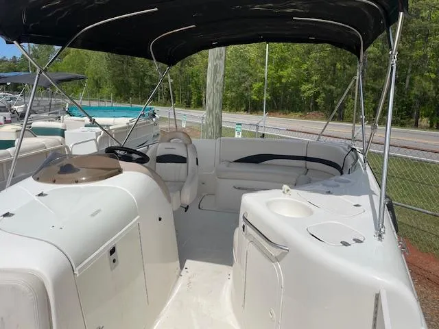 Slide: The Image of 2000 Chaparral Sunesta 232 boat interior with seating and canopy, parked near a fence. - 4