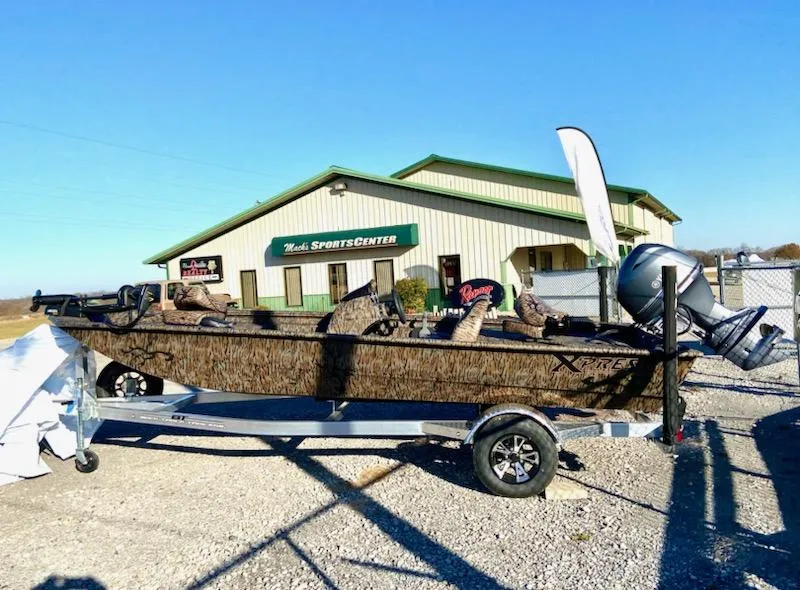 Slide: The Image of 2024 Xpress XP180 boat on trailer outside sports center, sunny day. - 1