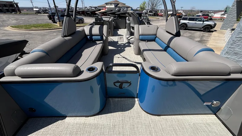 Slide: The Image of 2024 Tahoe Pontoon 2585 Cascade interior with gray and blue seating, docked outdoors. - 12
