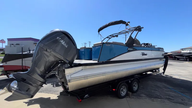 Slide: The Image of 2024 Tahoe Pontoon 2585 Cascade on trailer with Yamaha outboard motor, parked outdoors. - 2