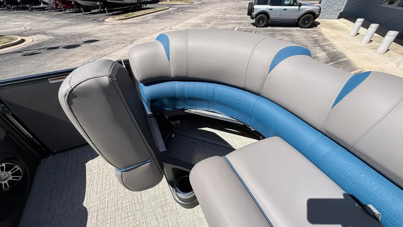 Slide: The Image of 2024 Tahoe Pontoon 2585 Cascade interior with gray and blue seating, parked outdoors. - 20