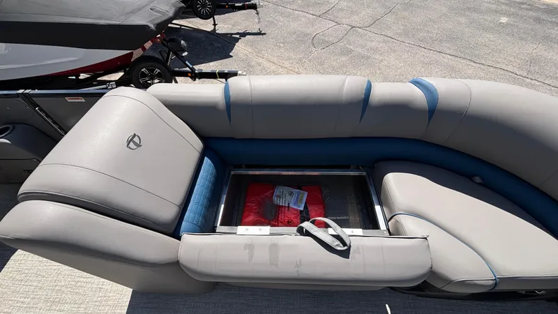 Slide: The Image of 2024 Tahoe Pontoon 2585 Cascade seating with storage compartment, gray upholstery, and blue accents. - 22