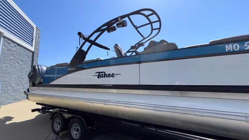 Slide: The Image of 2024 Tahoe Pontoon 2585 Cascade on trailer, side view under clear blue sky. - 3