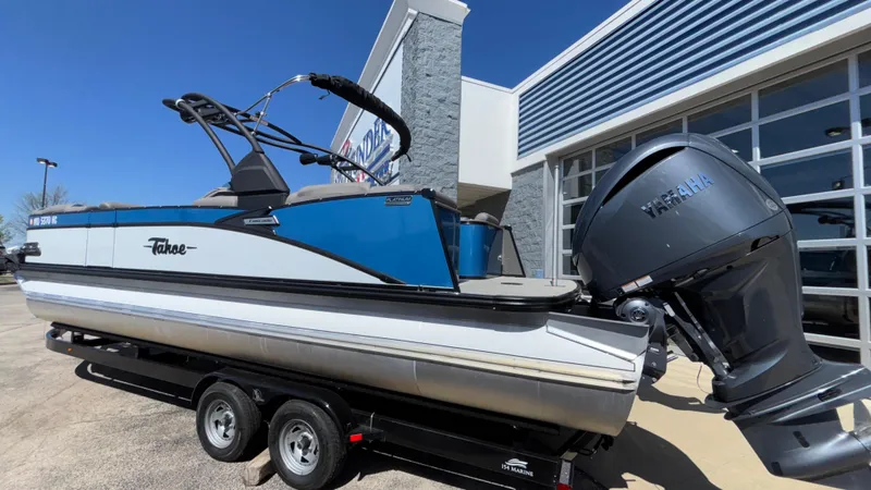 Slide: The Image of 2024 Tahoe Pontoon 2585 Cascade boat on trailer, blue and white design, parked outdoors. - 47
