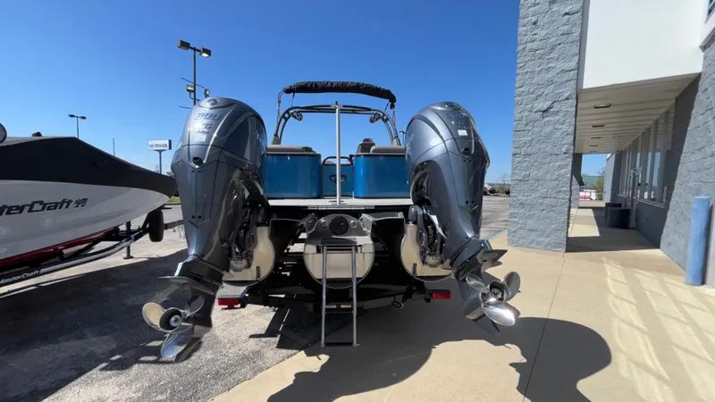 Slide: The Image of 2024 Tahoe Pontoon 2585 Cascade with dual outboard motors, parked outside a building. - 48