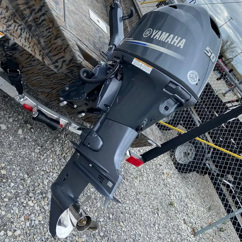 Slide: The Image of Yamaha 50HP outboard motor on Express H16DB 2024 boat, parked on gravel. - 2