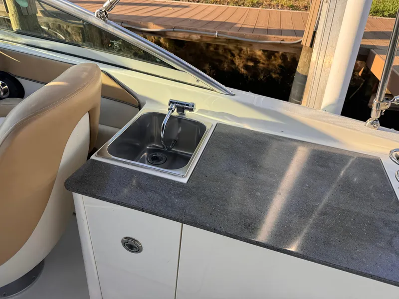 Slide: The Image of 2011 Sea Ray 280 Sundeck interior with sink and countertop, featuring beige seating. - 13