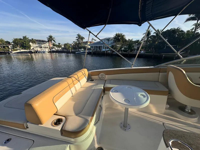 Slide: The Image of 2011 Sea Ray 280 Sundeck boat interior with seating and table, docked by waterfront homes. - 3