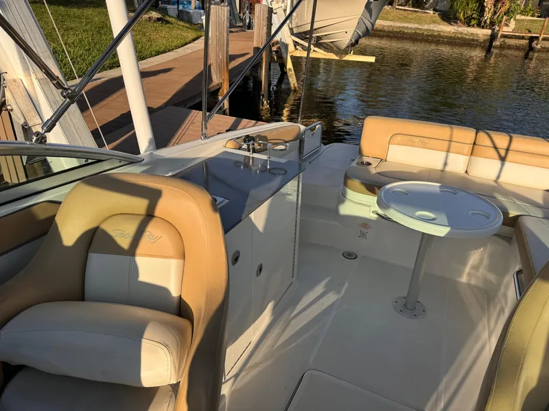 Slide: The Image of 2011 Sea Ray 280 Sundeck interior with seating and table, docked by the water. - 6
